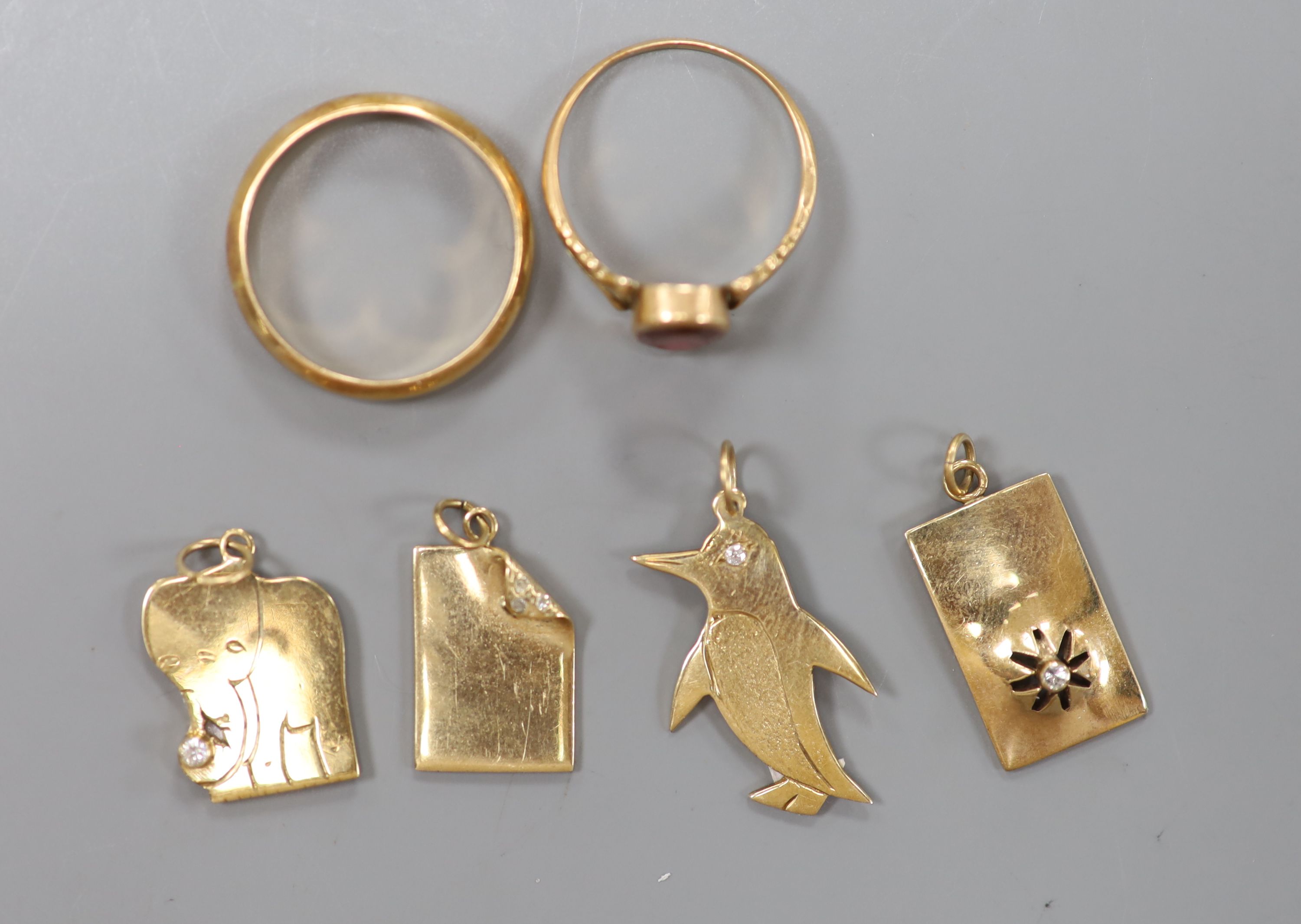 Four modern 9ct gold charms, a continental yellow metal wedding band and one other ring